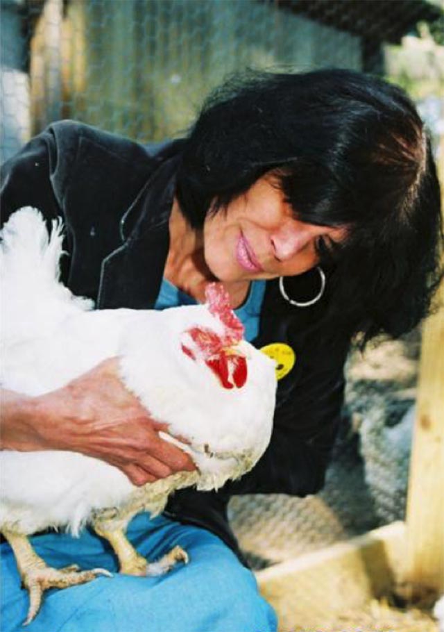 Karen sitting with a rescued hen in her lap