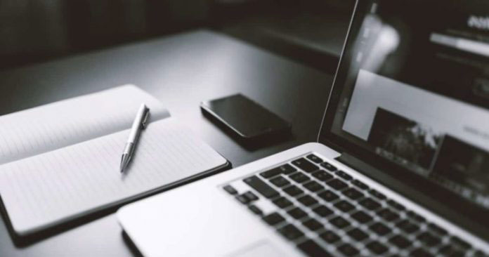 Laptop, notepad and pen on a desktop